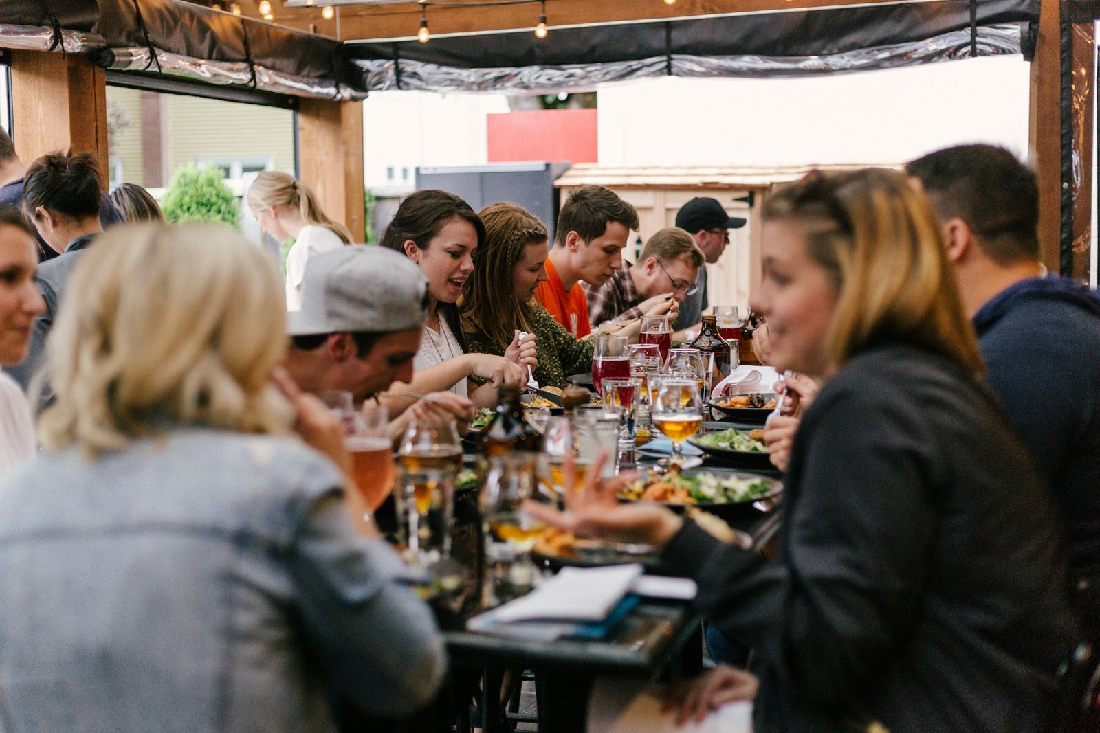 A group of friends celebrating at a long table, with beers and plates to share