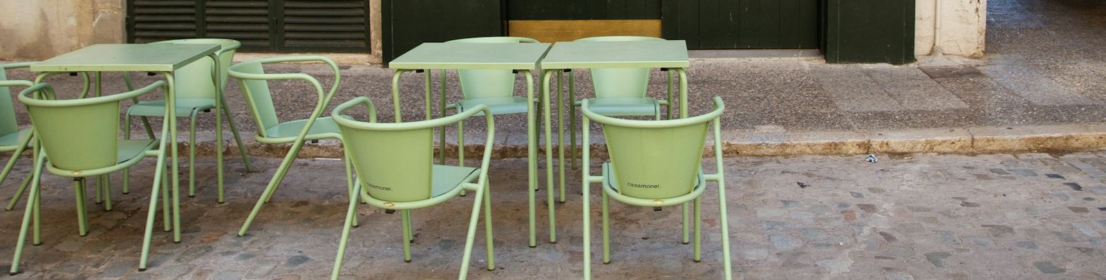 Terrace tables and green chairs on a cobbled street