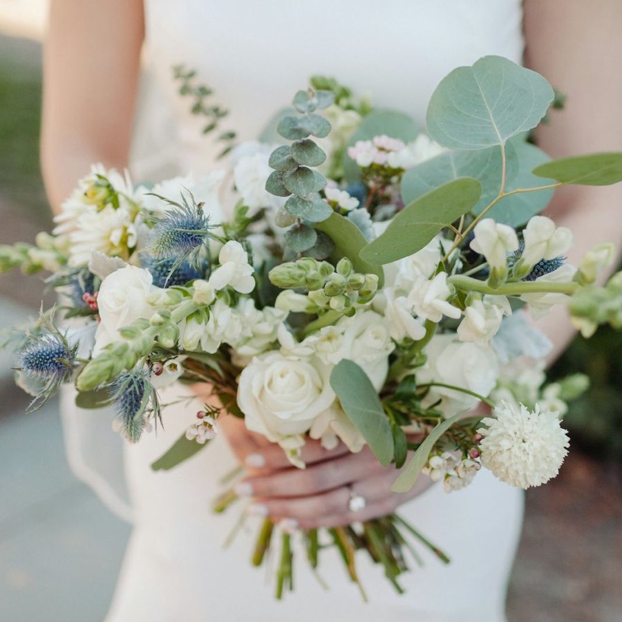 The bridal bouquet up close: white rose, blue sea holly, eucalyptus and loose greenery