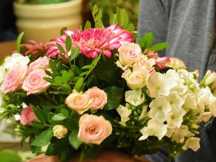 Round bouquet of roses, gerbera and white flowers held in two hands