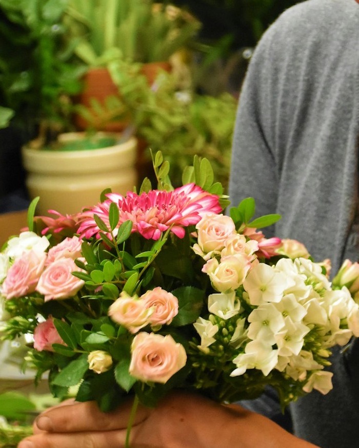 Round bouquet of pink roses, gerbera and white flowers held in both hands