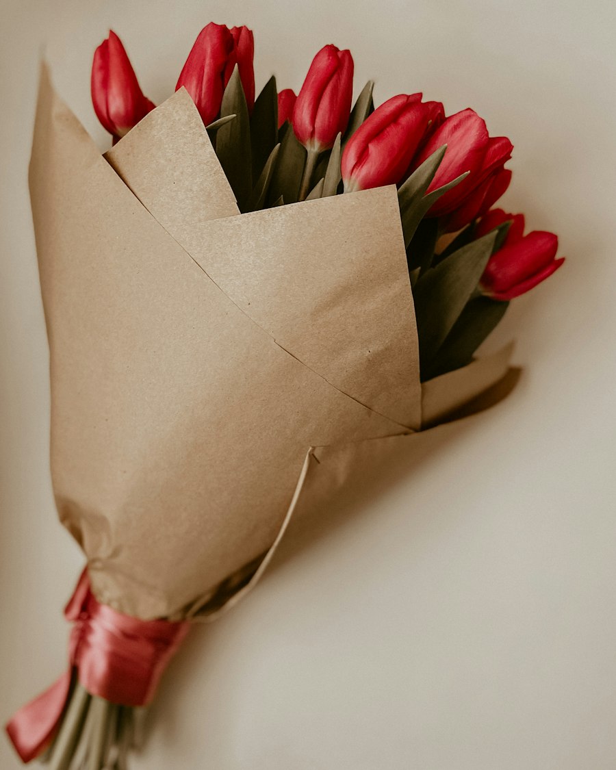 Tulipanes rojos envueltos en papel kraft, con una cinta roja en los tallos