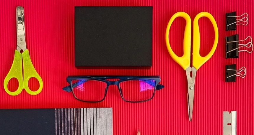 Scissors, clips and a pair of glasses on red card