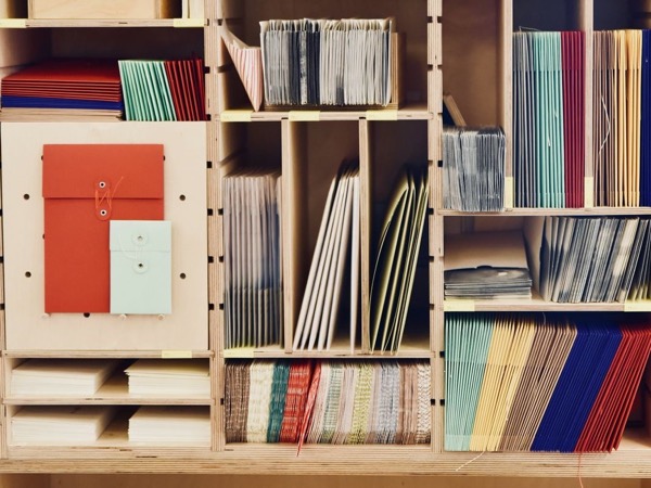 Wooden shelving with envelopes, folders and coloured paper