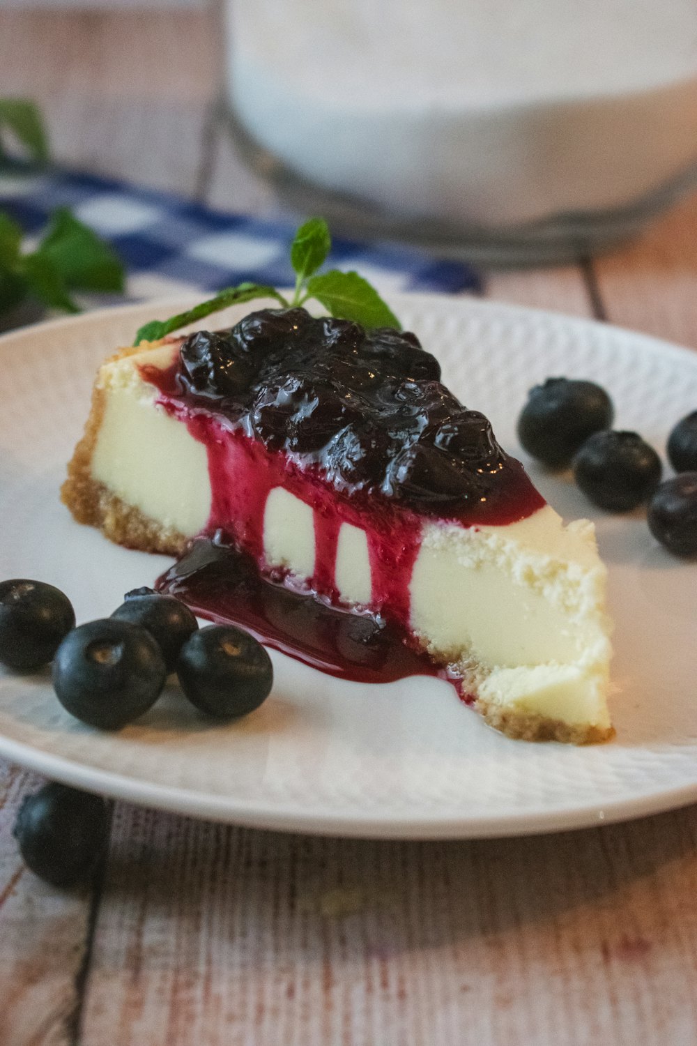 Porción de cheesecake con cobertura de arándanos y arándanos frescos alrededor