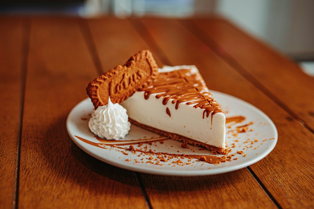 Porción de cheesecake con una galleta caramelizada y un poco de nata montada