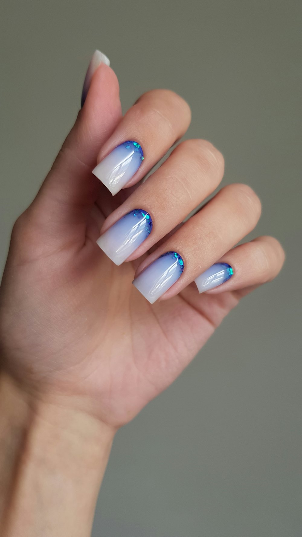 Mano con uñas en degradado de blanco a azul