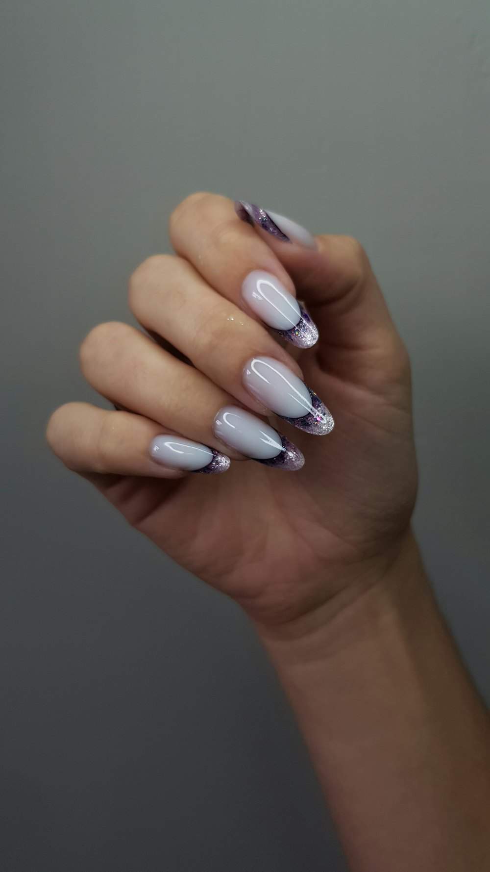 Mano con uñas largas en lila y detalles oscuros