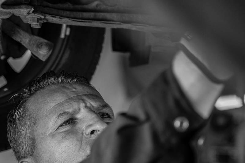 Mechanic inspecting the underside of the car