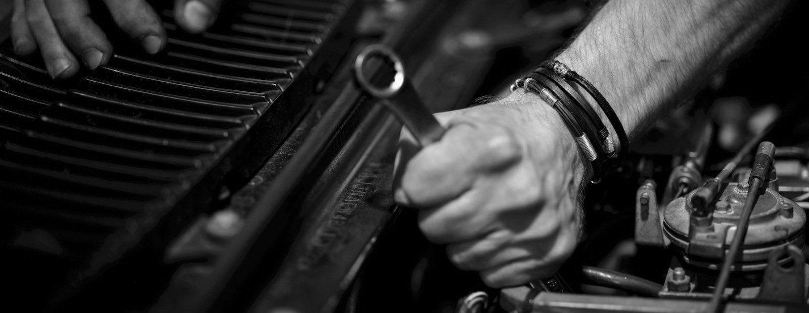 Mechanic’s hands with an open-ended spanner over the engine